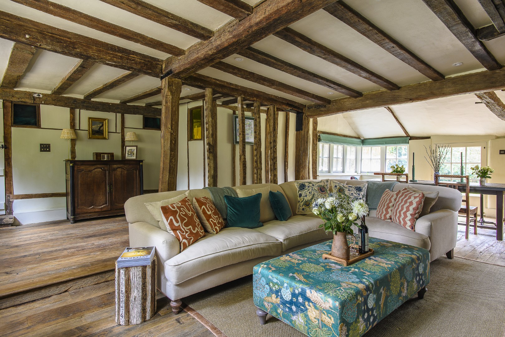 Comfy seating gathers around a large inglenook in the drawing room. Little pops of colour come courtesy of stained glass windows on the back wall, installed during Brian Jones’ occupation