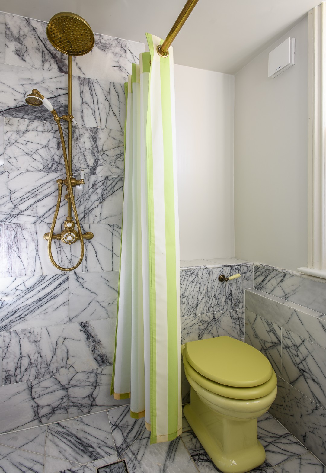 Veined Carrara marble tiles from Mandarin Stone and coloured sanitaryware make wonderful statements throughout the property