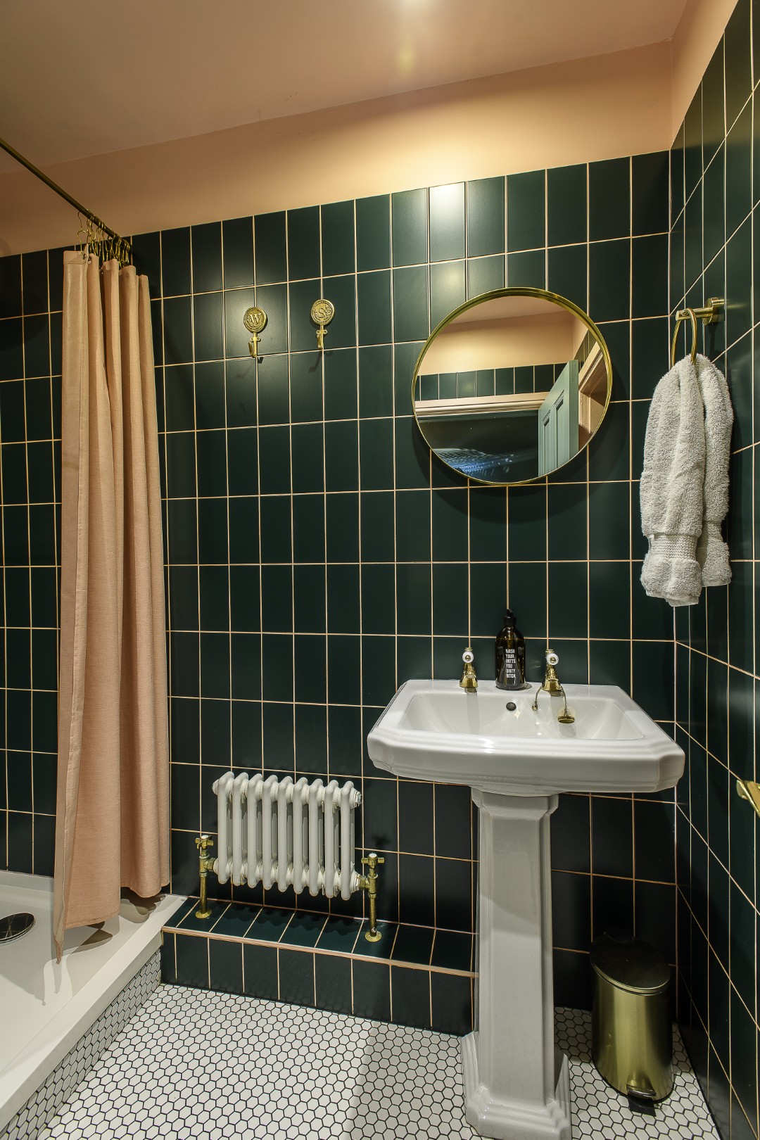 The shower room next door is tiled in forest green, lightened with blush pink paint