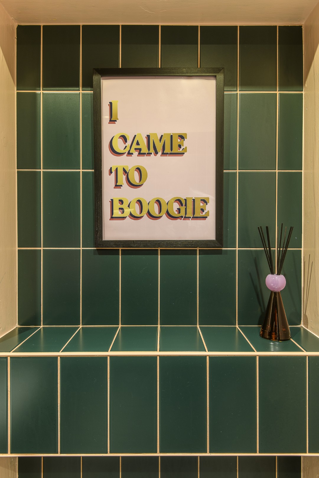 The shower room next door is tiled in forest green, lightened with blush pink paint