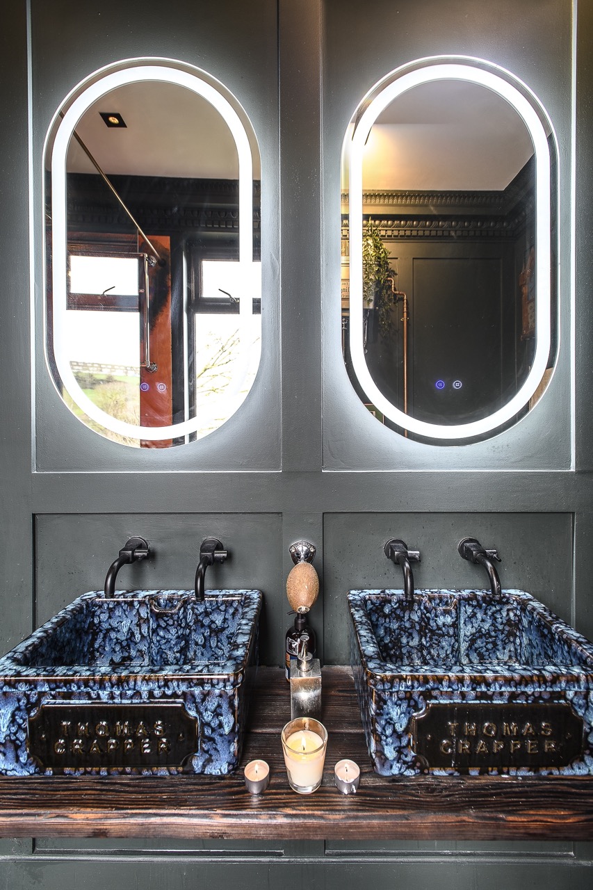 The shower room continues the drama. Twin Thomas Crapper basins in blue sit atop another yakisugi timber support, complemented by matt black Dyke & Dean fittings