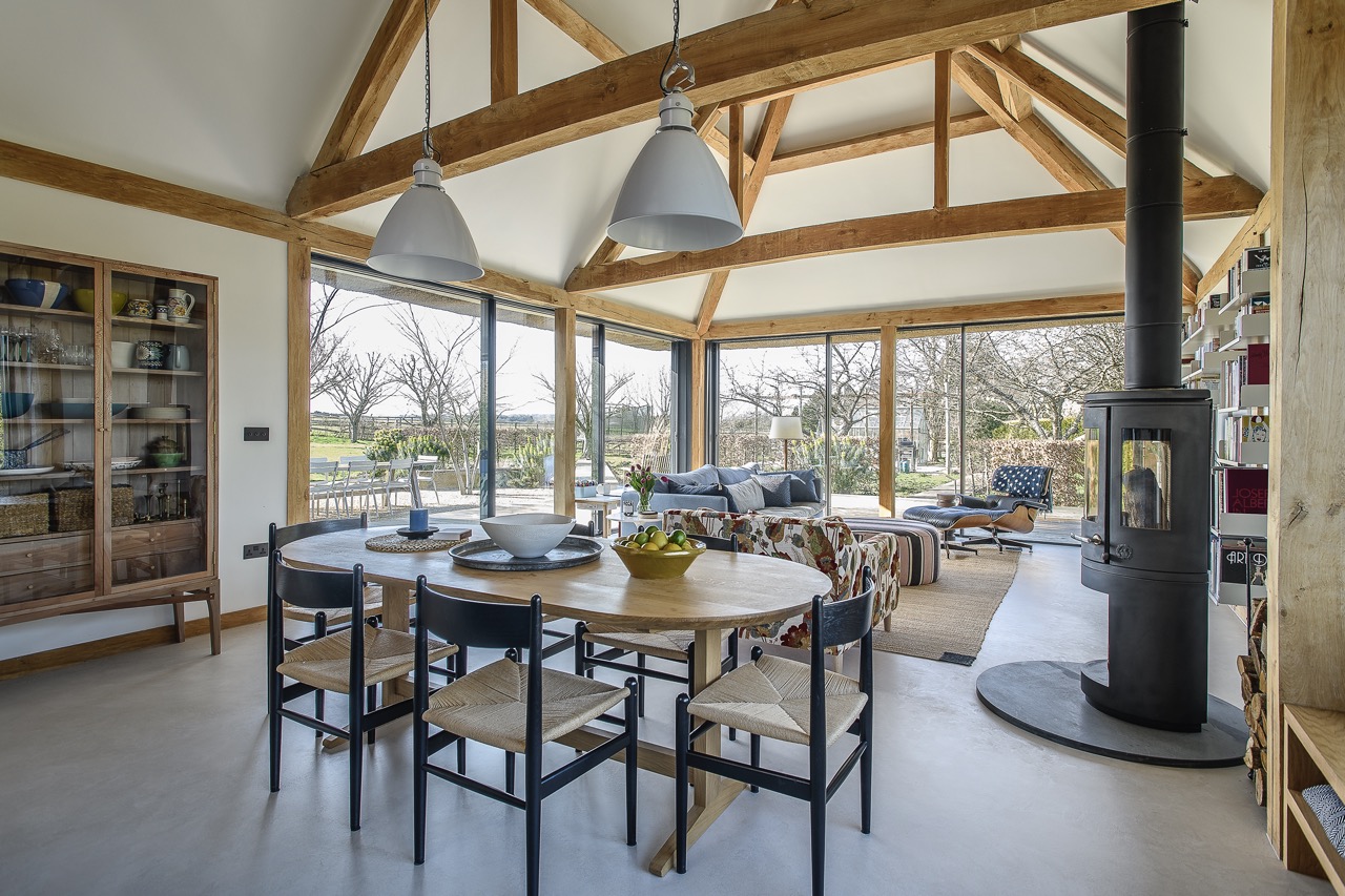 A blue kitchen by Fallow Workshops nestles neatly into the timber structure of the barn.