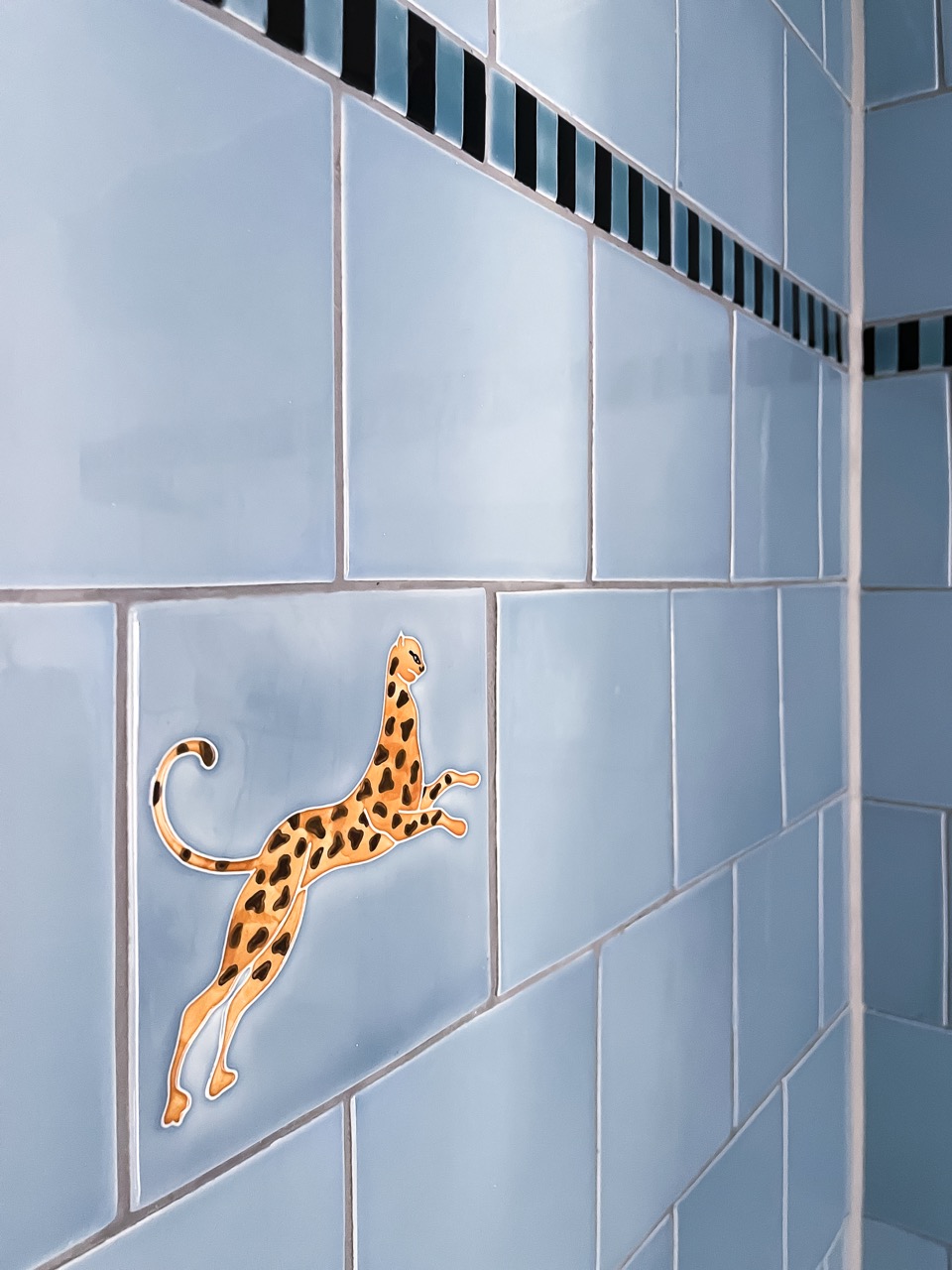 playful leopard tiles in the shower and a twin basin unit
