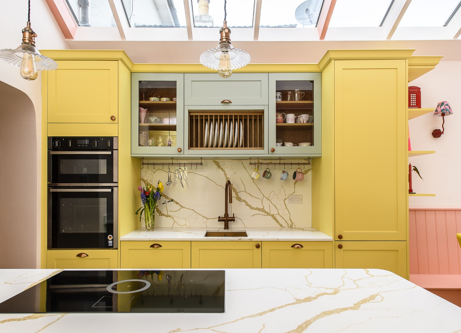 The yellow kitchen cabinets were echoed on the other side of the room, where full-height storage and extra worktop space fit neatly in alongside the telephone box drinks cabinet