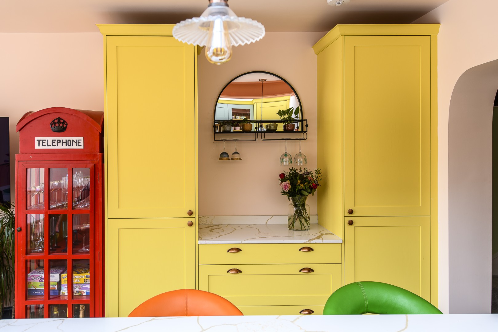 The yellow kitchen cabinets were echoed on the other side of the room, where full-height storage and extra worktop space fit neatly in alongside the telephone box drinks cabinet