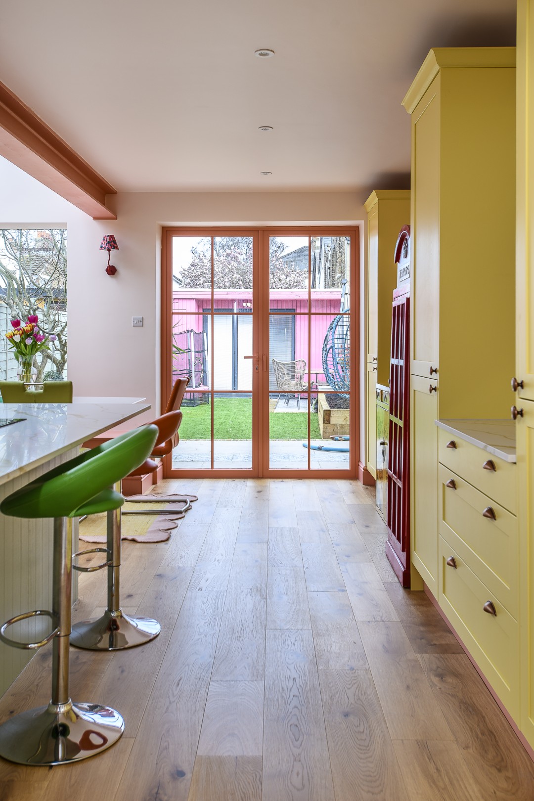 The yellow kitchen cabinets were echoed on the other side of the room, where full-height storage and extra worktop space fit neatly in alongside the telephone box drinks cabinet