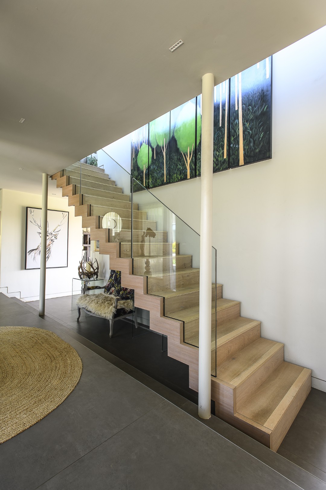 A laminated birch ply and glass staircase leads up to the first floor