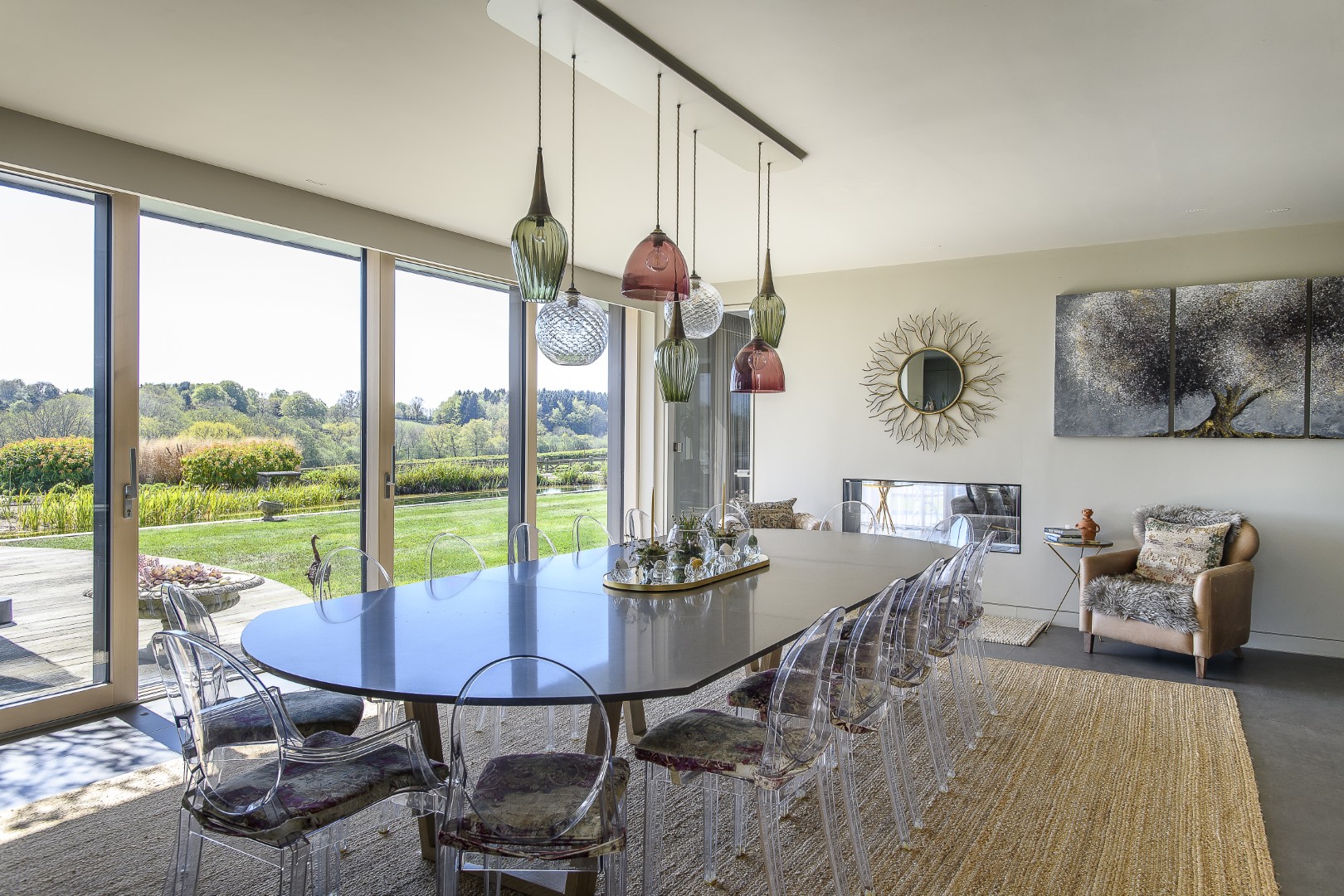 In the dining area a large table is surrounded by iconic Philippe Stark Ghost chairs by Kartell whilst a cluster of glass pendants from Rothschilds & Bickers hang above
