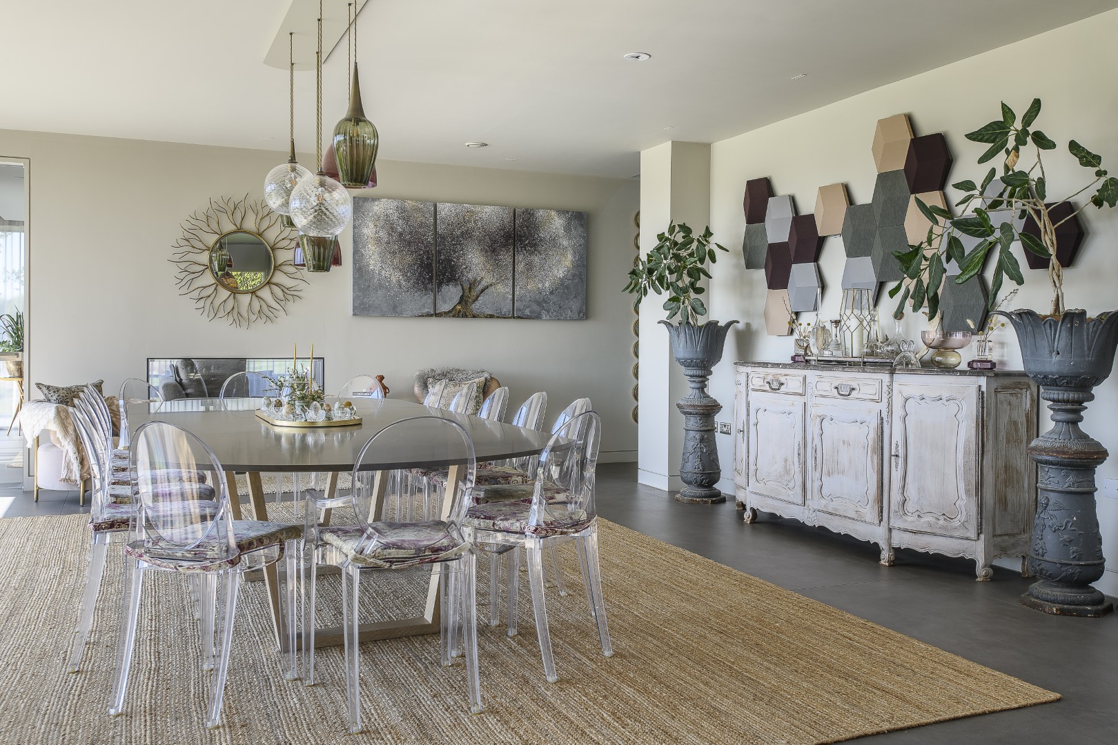 In the dining area a large table is surrounded by iconic Philippe Stark Ghost chairs by Kartell whilst a cluster of glass pendants from Rothschilds & Bickers hang above