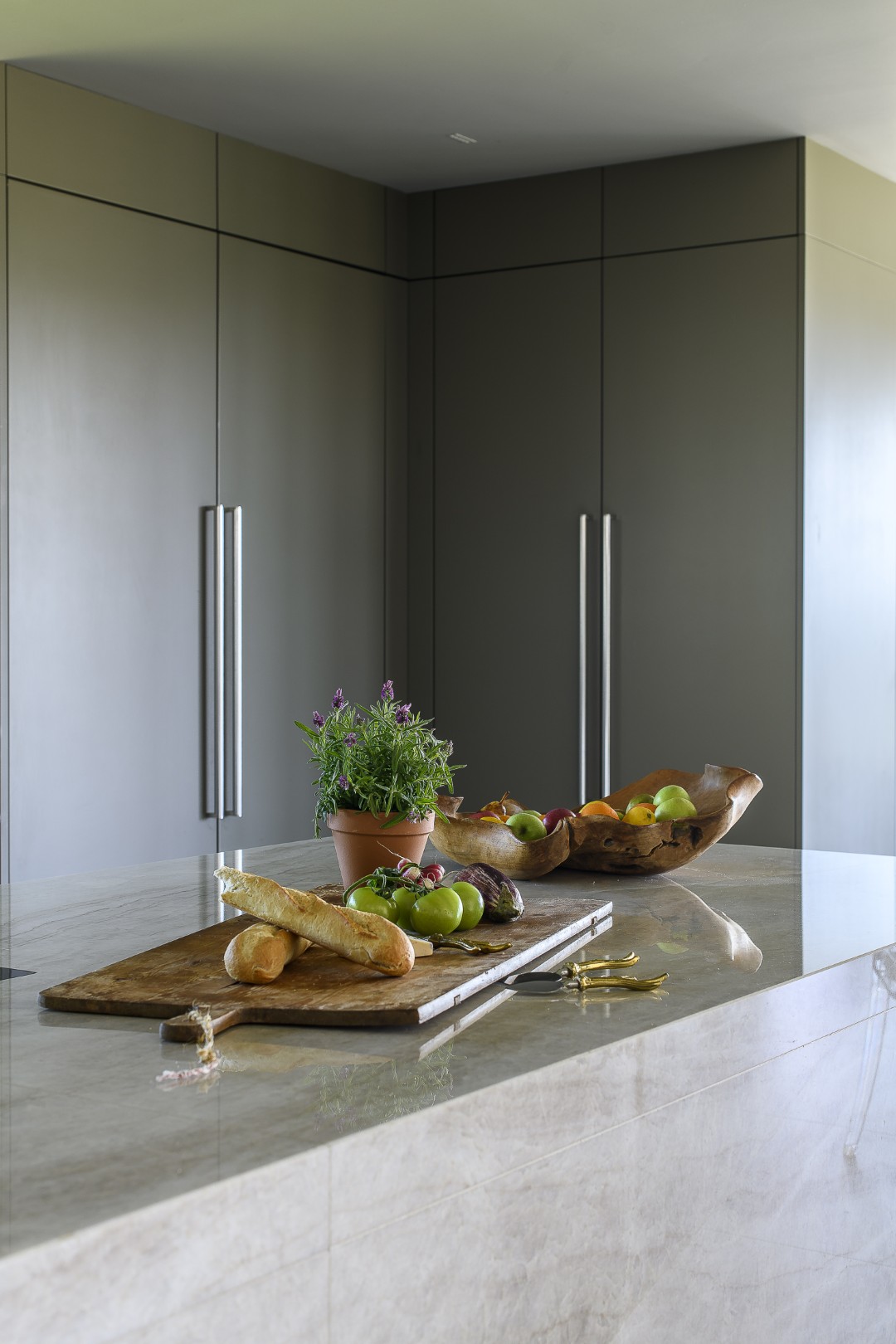 Cabinets are painted a deep grey-green that echoes the natural tones of the surrounding landscape