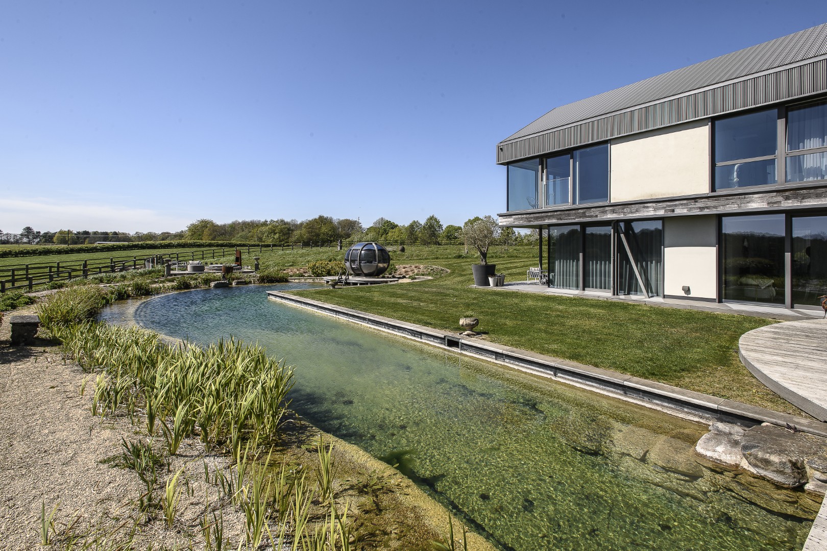 A natural swimming pond, created by Gartenart, anchors the space, its softly contoured edges avoiding any sense of formality.