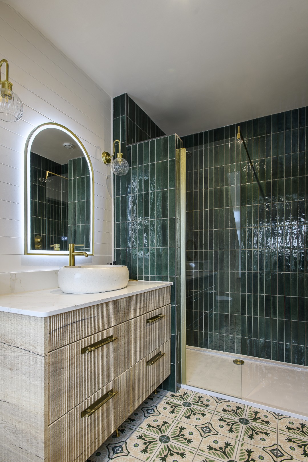 Dark green shower tiles join patterned Moroccan-style floor tiles to echo the principal bedroom’s tones in the en suite