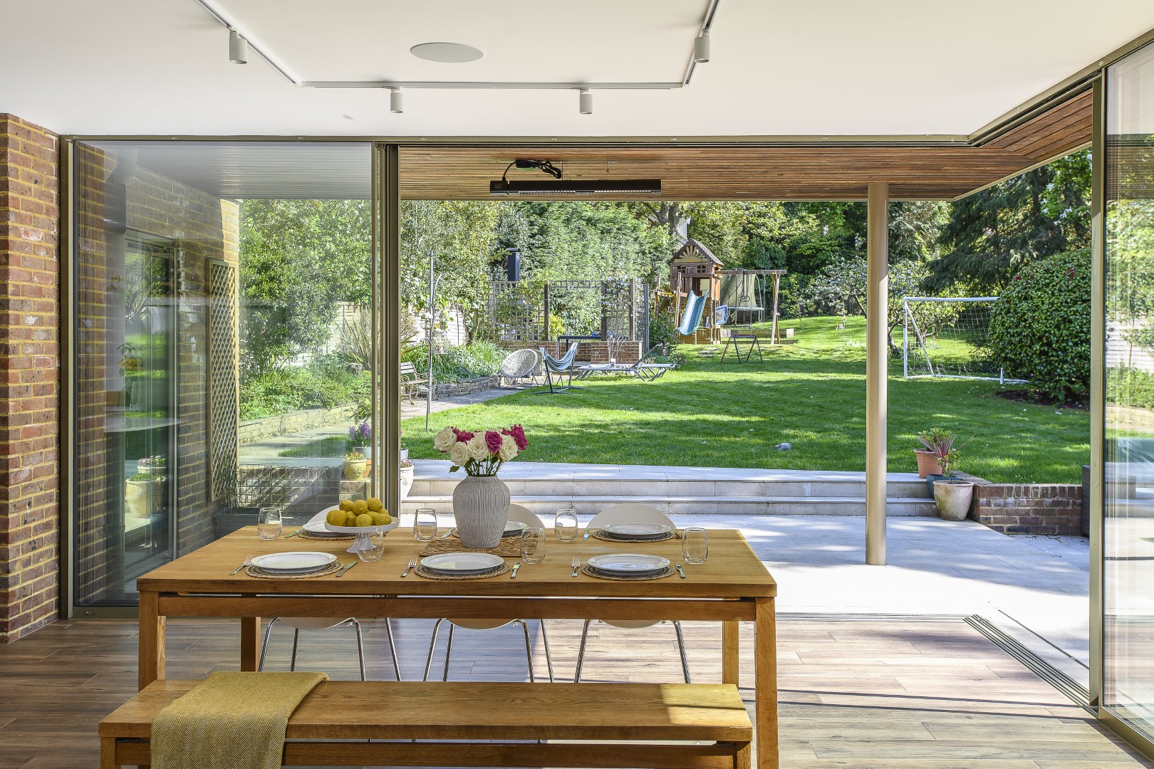 Exposed brickwork echoes the materials of the existing property, while warm oak detailing softens the contemporary glazing.