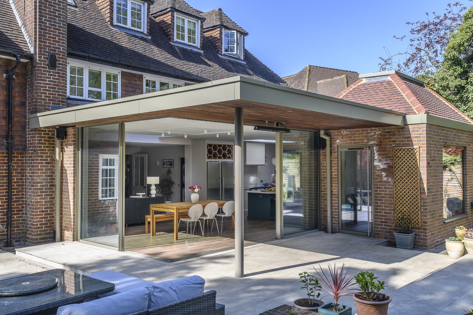Exposed brickwork echoes the materials of the existing property, while warm oak detailing softens the contemporary glazing.