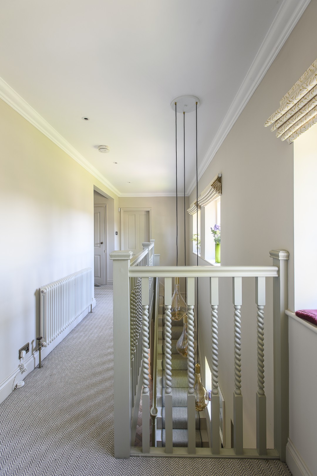 A trio of glass pendant lights stretch down over the staircase