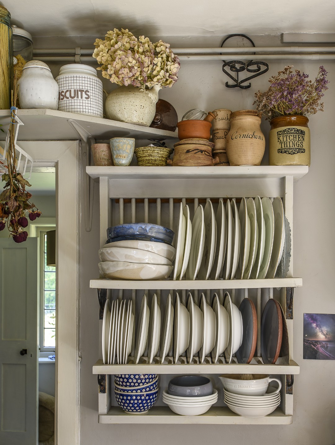 Plates and bowls stack neatly into an open plate rack below pots, vases and jugs up high.