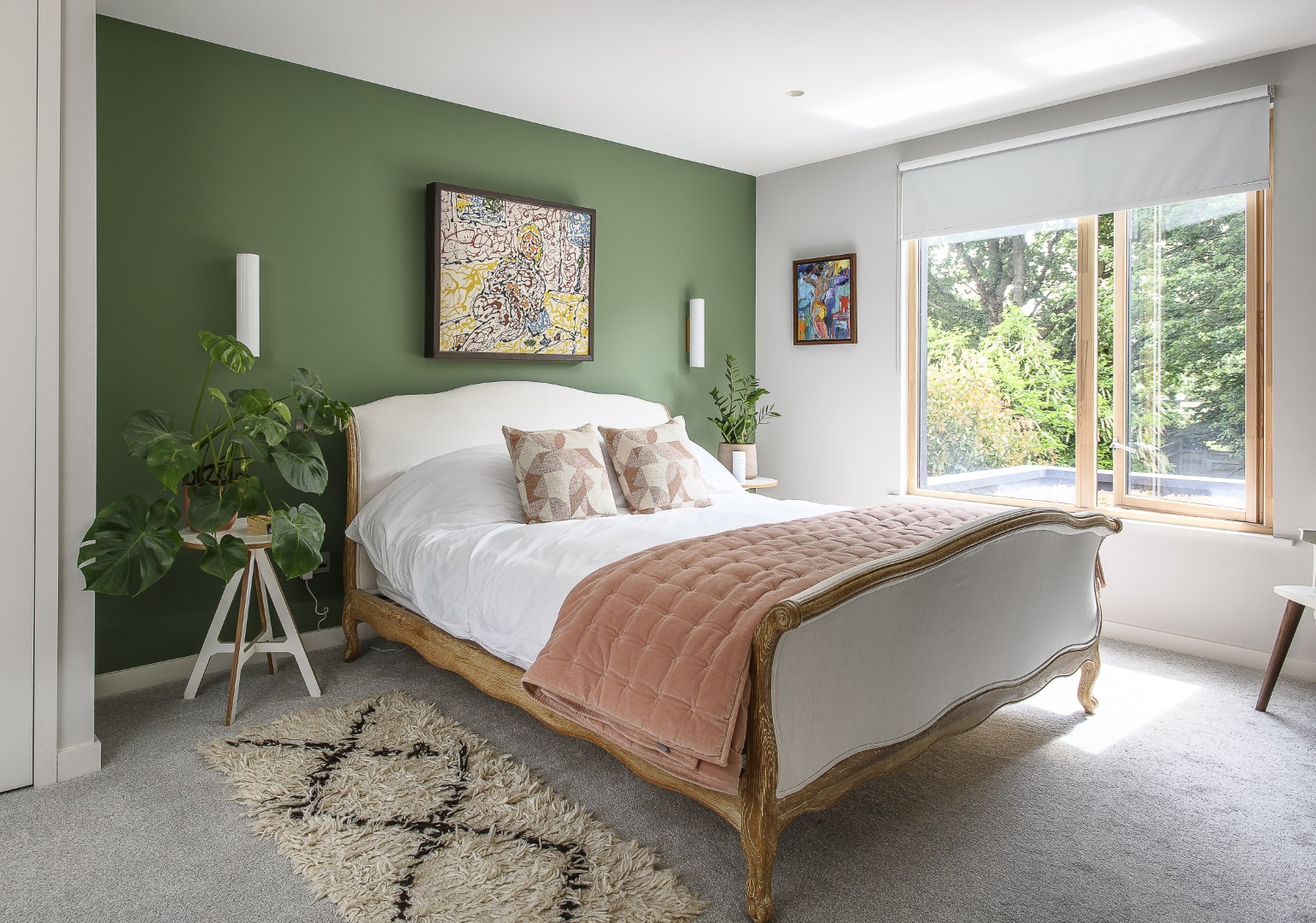 Thriving houseplants complement the rich green wall in the principal bedroom.