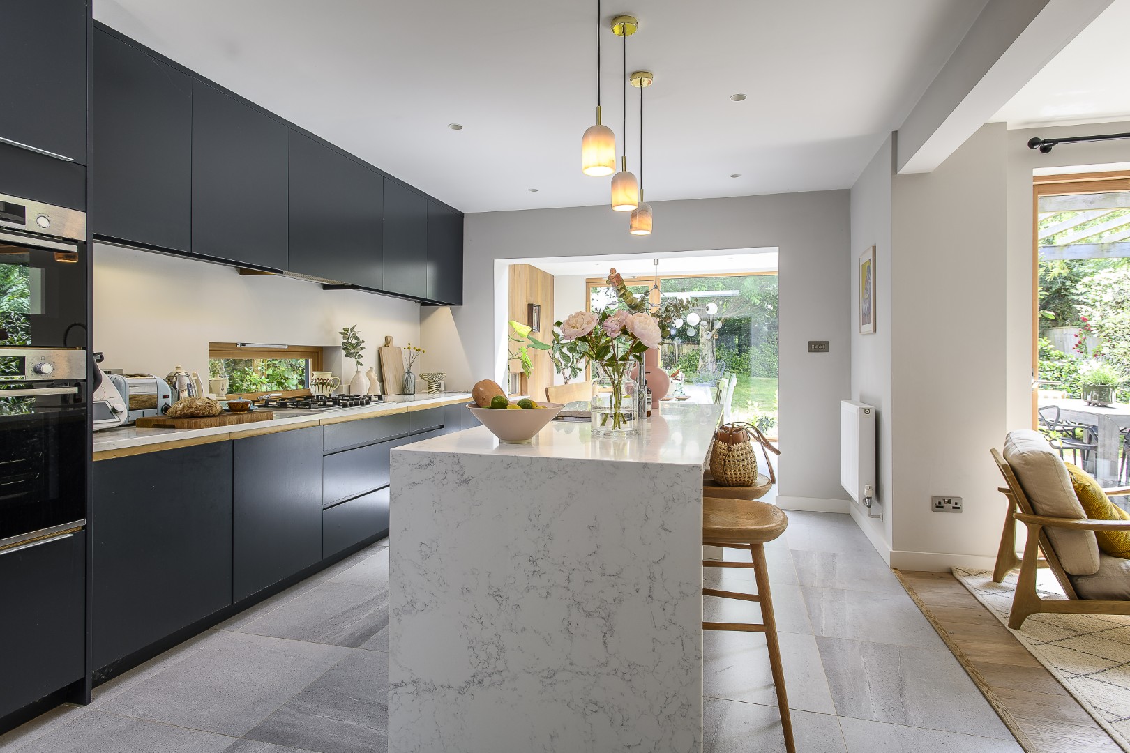 The kitchen has been painted a deep navy, in contrast to the pale marble of the island and flooring.