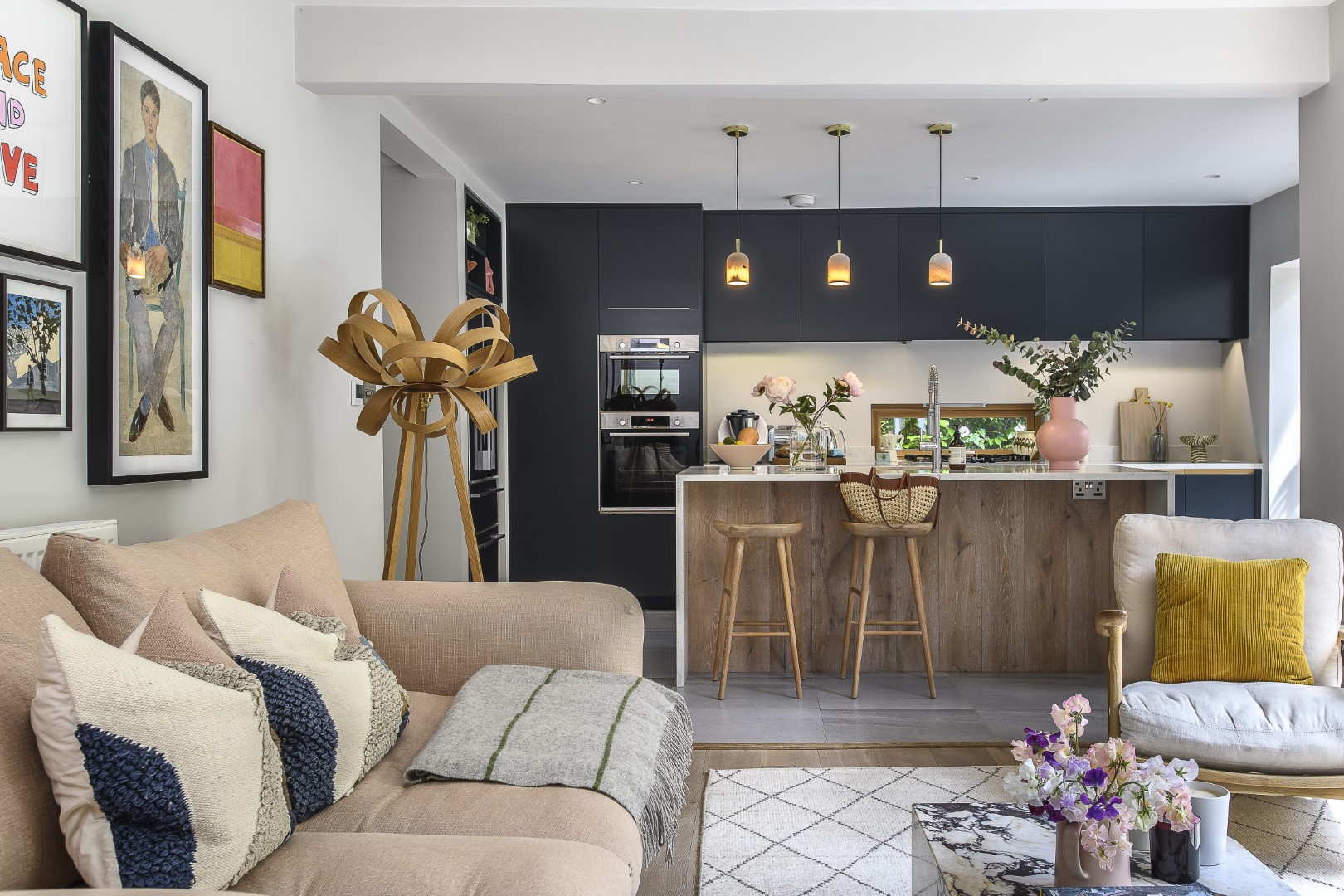 A Tom Raffield ‘Skipper’ floor light stands next to the blush pink sofa.